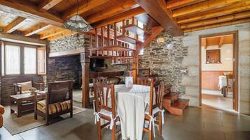 A rustic interior with a stone fireplace, wooden dining table, and chairs.