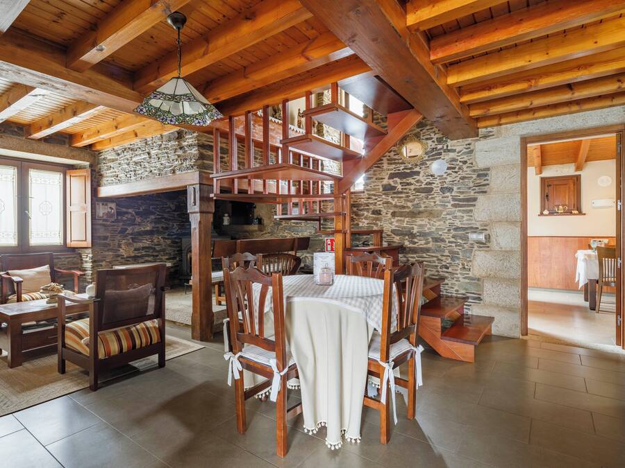 A rustic interior with a stone fireplace, wooden dining table, and chairs.