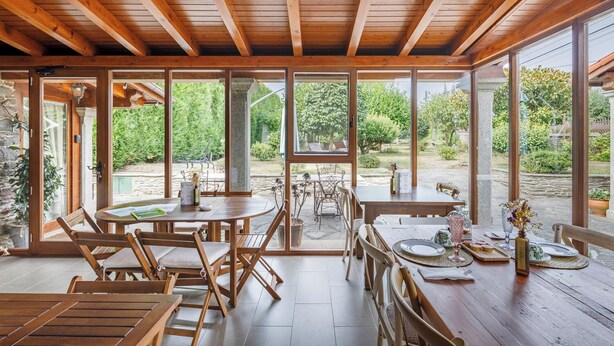 Comedor tipo loft con mesas y sillas de madera, amplias ventanas con vistas al jardín.