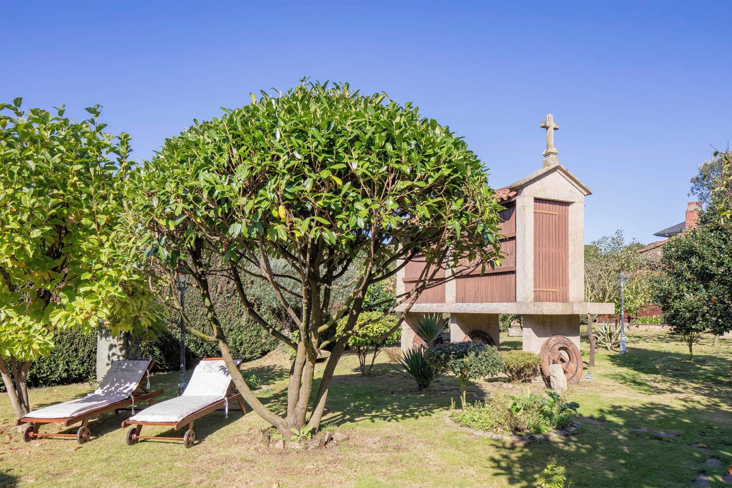 A garden with a small building, possibly a chapel, and two lounge chairs.
