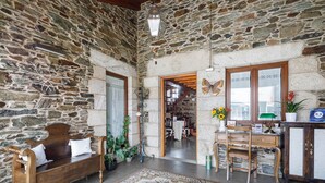 Una habitación con paredes de piedra, un banco de madera, un escritorio y una alfombra grande con motivos.