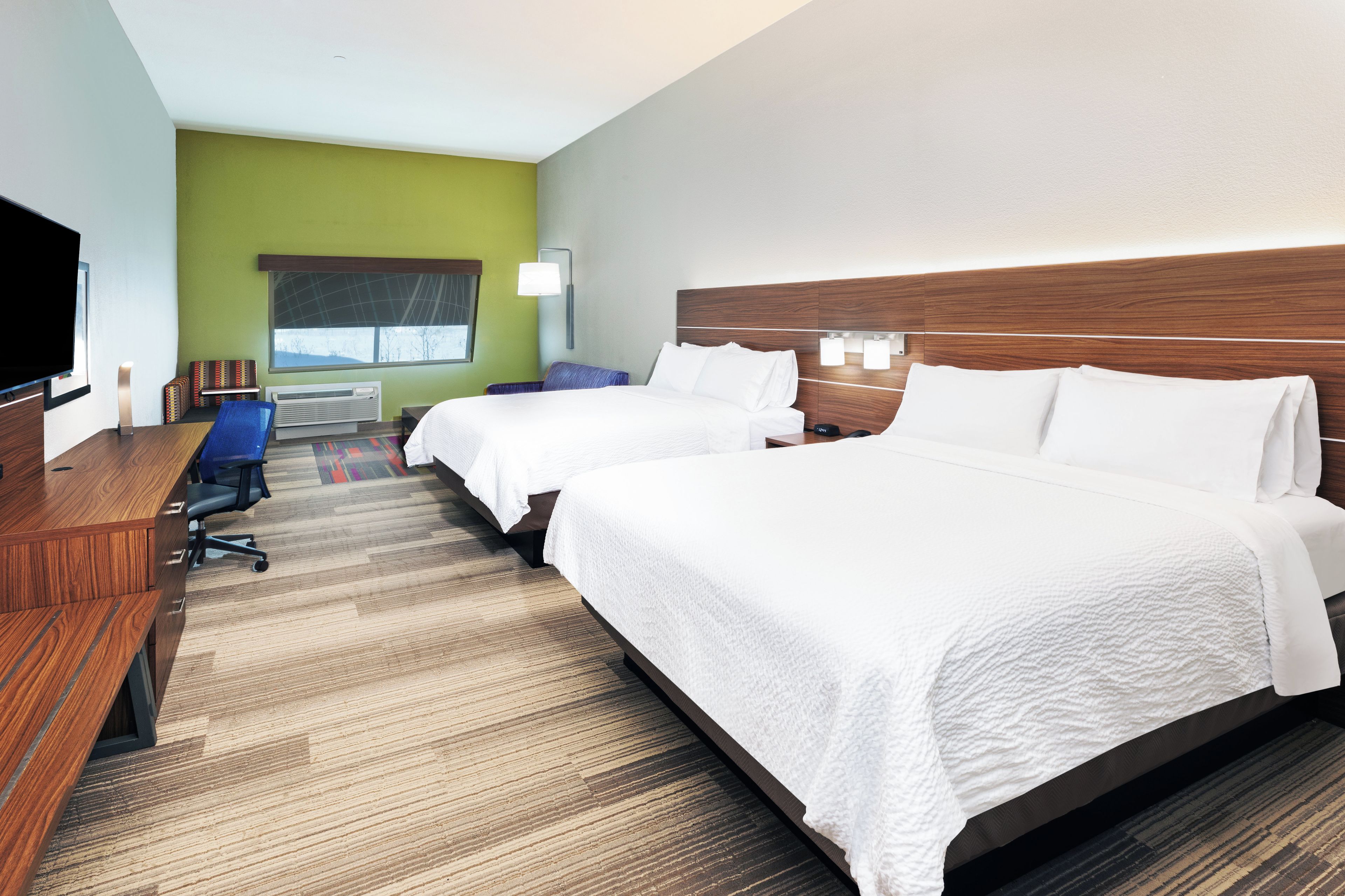 Habitación de hotel con dos camas, un escritorio, una televisión y una ventana con vistas.