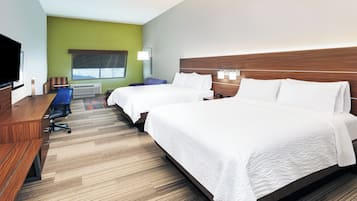Habitación de hotel con dos camas, un escritorio, una televisión y una ventana con vistas.