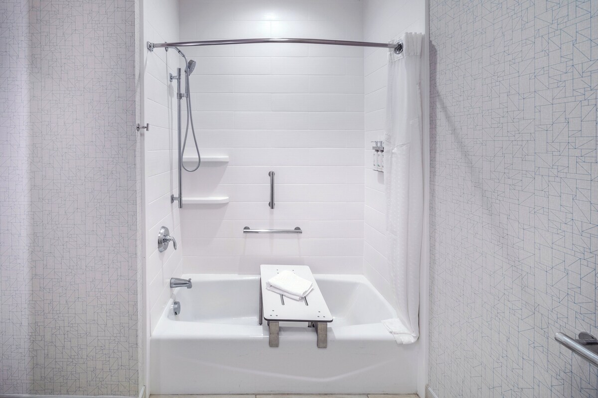 A modern shower with a glass door, a handheld showerhead, and a handheld shower attachment.