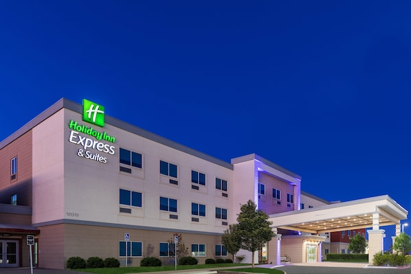 A Holiday Inn Express & Suites building with a modern facade, multiple windows, and a covered entrance area.