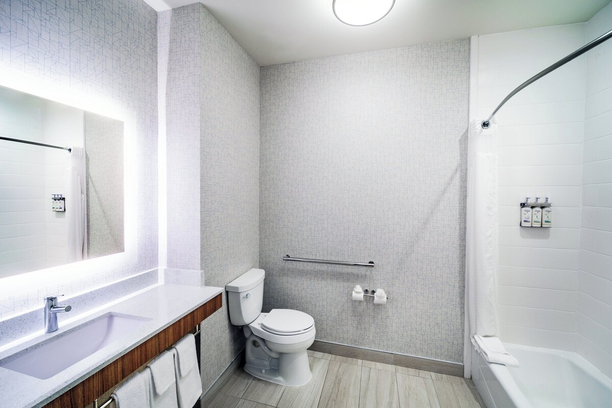 A modern bathroom with a shower, toilet, and sink.
