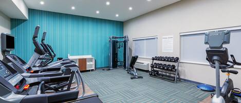 A fitness center with treadmills, a weight bench, dumbbells, and exercise equipment.