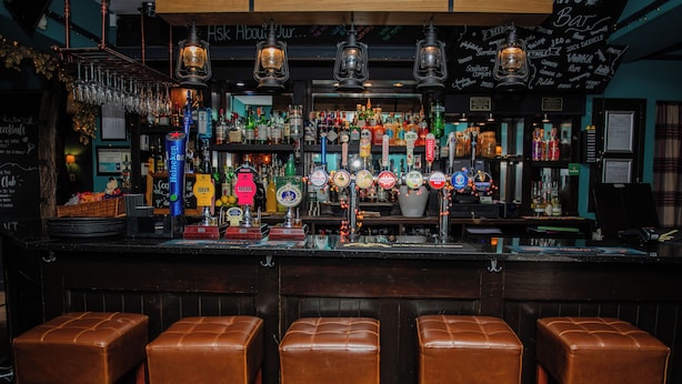 A bar with multiple beer taps, stools, and a variety of bottles and glasses. - Grantham Arms (York)