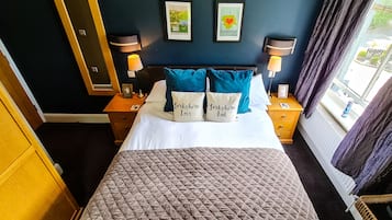 A hotel room with a bed, two bedside tables with lamps, a mirror, and framed pictures on the wall.