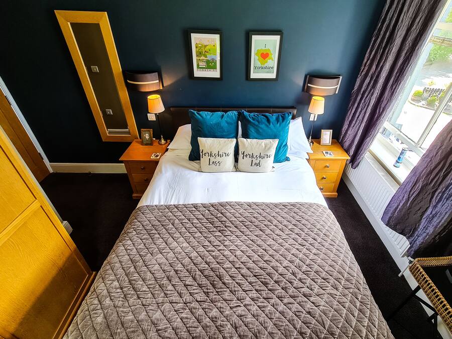 A hotel room with a bed, two bedside tables with lamps, a mirror, and framed pictures on the wall.