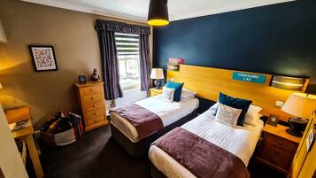 A hotel room with two beds, a dresser, a lamp, and a sign indicating the location as Yorkshire.