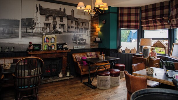 Un acogedor interior de pub con un mural de un coche clásico, muebles de madera y una chimenea.