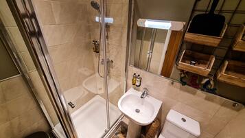 Een badkamer met een douchecabine van glas, een wastafel en een toilet.
