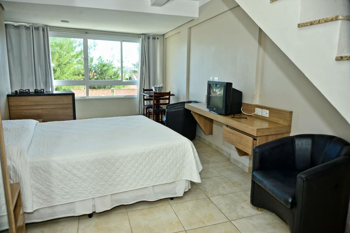 A hotel room with a bed, a desk with a computer, a chair, and a TV.