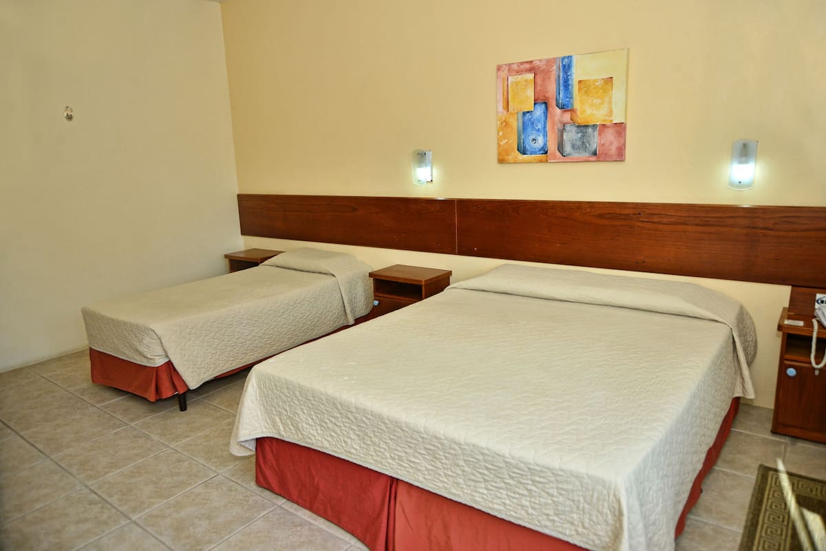 A hotel room with two beds, a wooden headboard, a wall-mounted artwork, and bedside lamps.