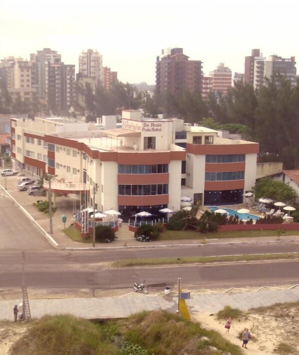 A hotel with multiple floors, outdoor seating, and a swimming pool.