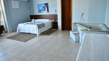 Quarto de hotel com uma cama, banheiro com banheira, porta de madeira e ar-condicionado fixado na parede.