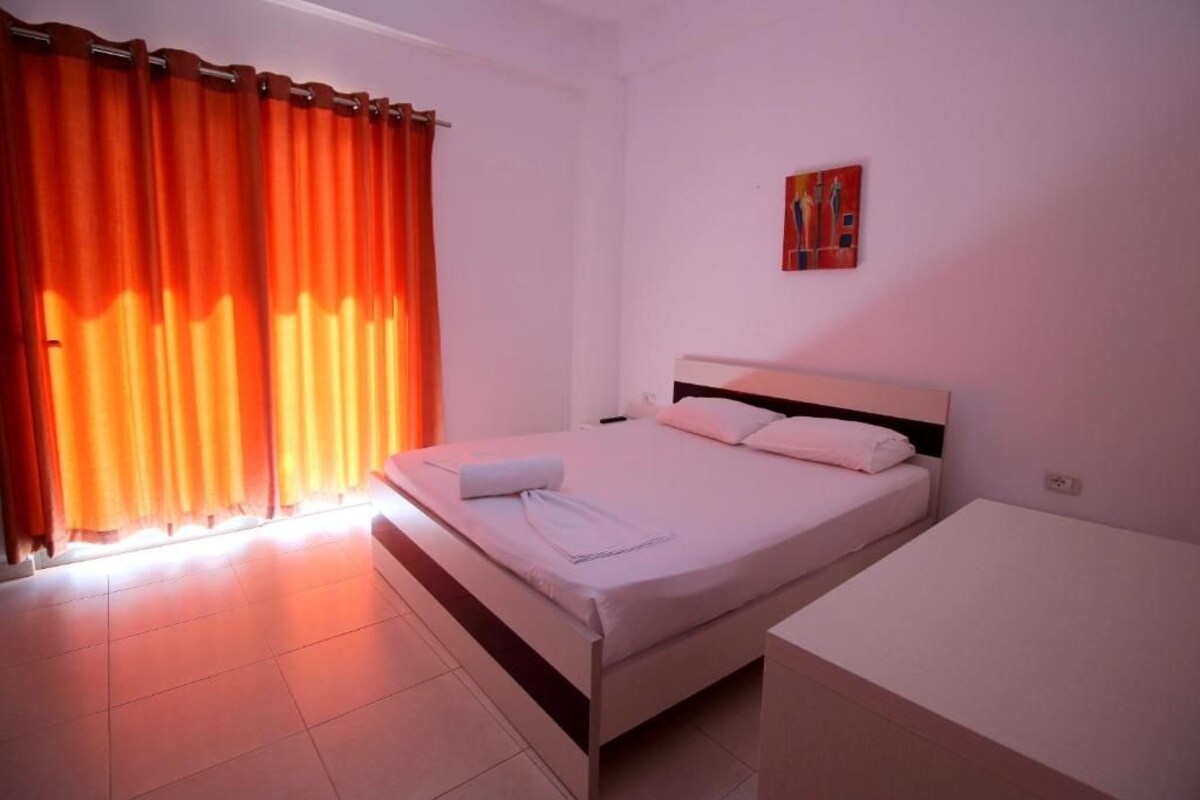 A bedroom with a bed, a bedside table, and a window with curtains.