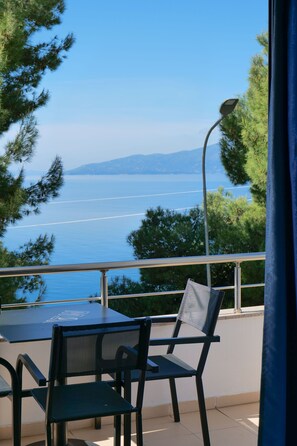 A balcony with a table and chairs overlooking a body of water and mountains. - Hotel Argjiro (Sarandë)