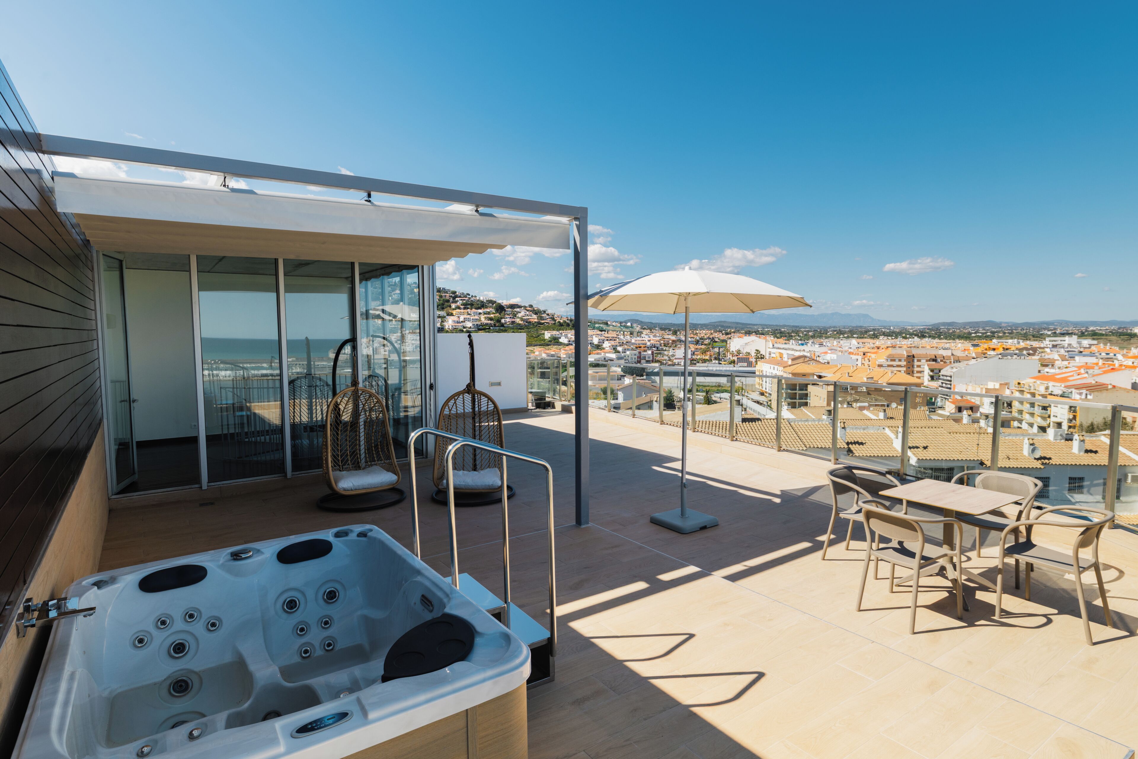 A rooftop terrace with a hot tub, seating area, and a view of the city.