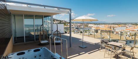 A rooftop terrace with a hot tub, seating area, and a view of the city.