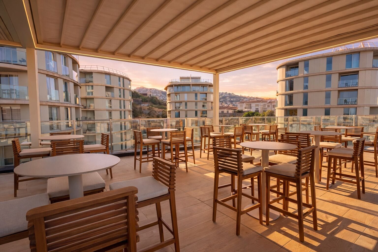 Een terras op het dak met houten tafels en stoelen, met uitzicht op een stadsgezicht met moderne gebouwen.