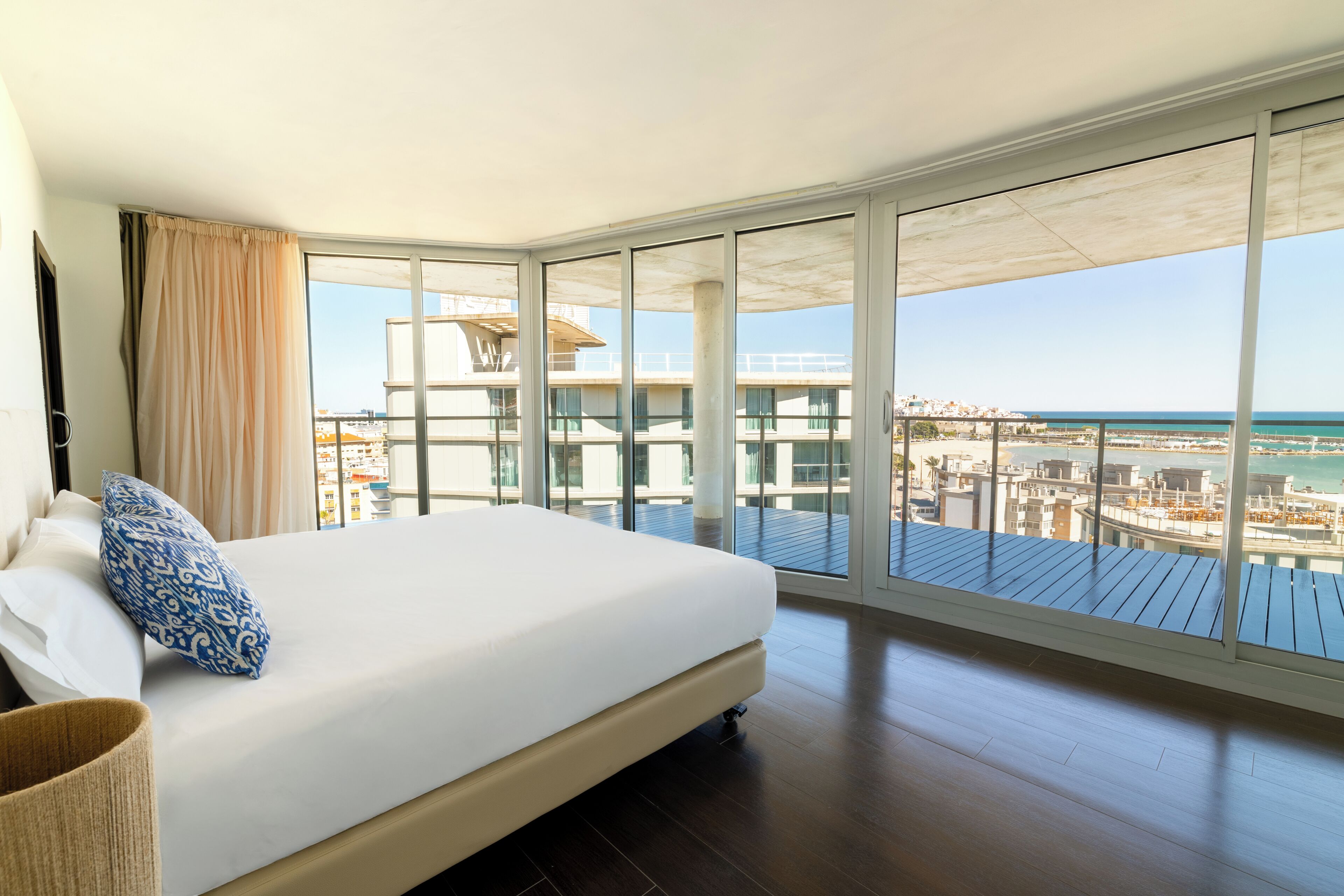 Un dormitorio con una cama grande, vistas al mar y un balcón con cubierta de madera.