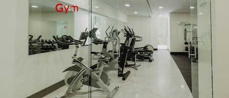 A gym with exercise machines, a mirrored wall, and a clean, modern design.