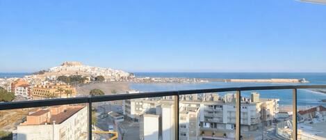 A balcony with a view of a coastal cityscape, including buildings and a beach.
