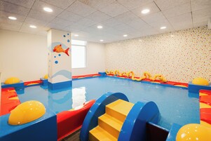 Una piscina interna con scivoli e scalini, un murale a tema pesce e un muro rivestito di piastrelle.