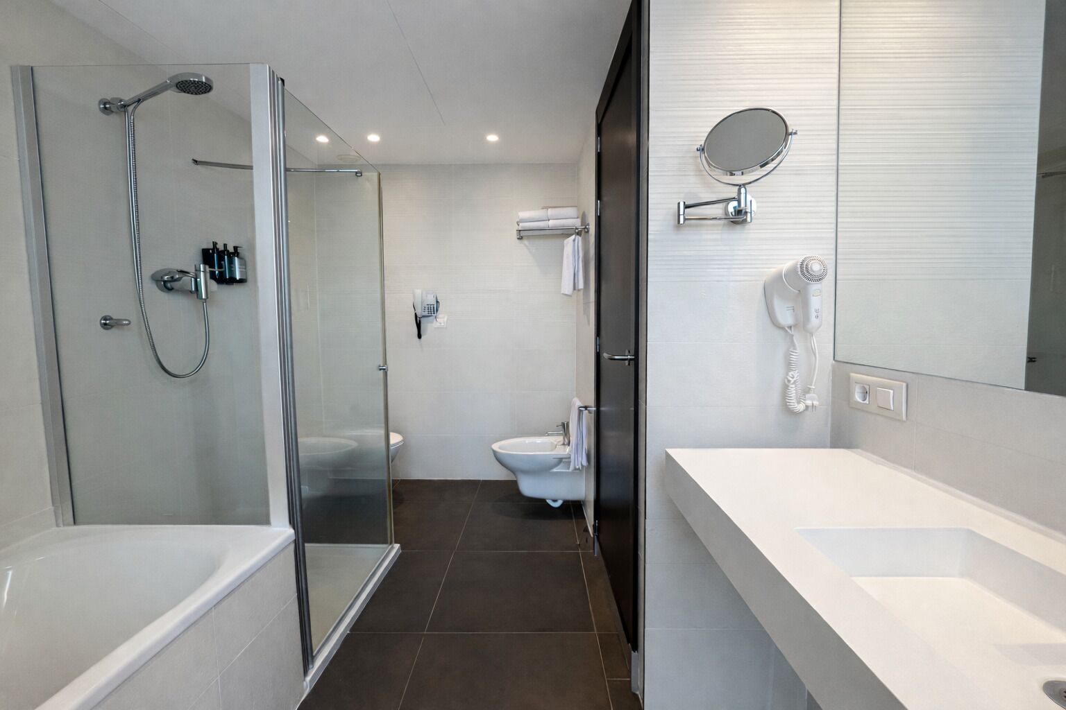 A modern bathroom with a glass-enclosed shower, a toilet, and a sink with a mirror.