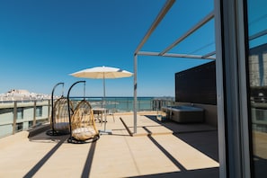 A balcony with a view of the sea, a white umbrella, wicker chairs, and a hot tub. - Palladium Hotel Peñíscola (Peniscola)