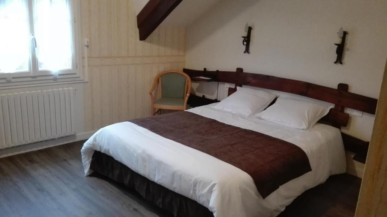 Een slaapkamer met een bed, een stoel, een radiator en een raam.