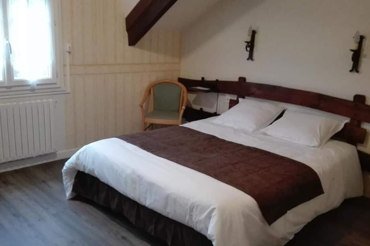 Une chambre à coucher avec un lit, une chaise, un radiateur et une fenêtre.