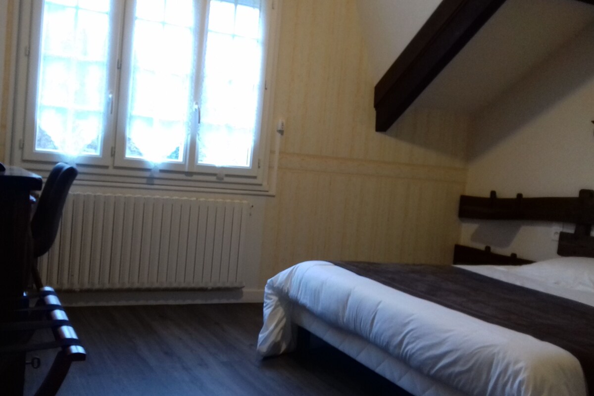 Une chambre avec un lit, un bureau et une fenêtre avec des stores.