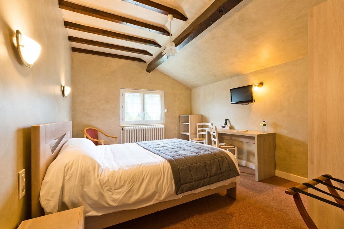 Une chambre à coucher avec un lit, un bureau, une chaise, une télévision et une fenêtre.