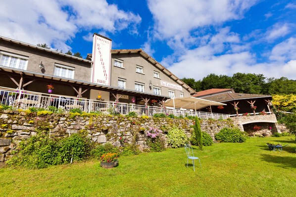 Een hotel met een gevel van natuursteen, terras en een tuin.