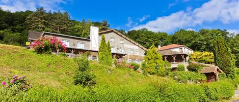 Un hotel con varias construcciones en una ladera, rodeado de abundante vegetación y árboles.