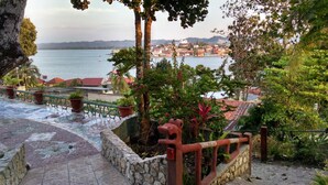 A terraced outdoor area with stone walls, potted plants, and a view of a coastal town.