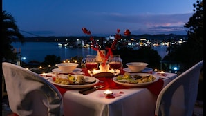 A table set for two with a view of a cityscape at dusk.