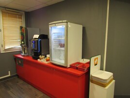 Una pequeña zona de kitchenette con cafetera, refrigerador y microondas.