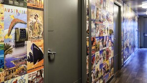 Un couloir aux murs ornés d’affiches de voyage, une porte et un plancher en bois.