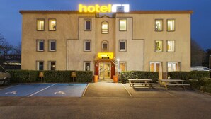 Un bâtiment d’hôtel avec une enseigne indiquant « hôtel », une place de stationnement accessible aux personnes à mobilité réduite et une table de pique-nique.
