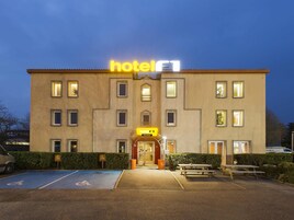 Un edificio de hotel con un cartel que dice 'hotel', un espacio de estacionamiento accesible para sillas de ruedas y una mesa de picnic.