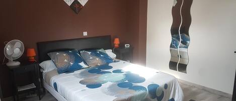 A bedroom with a bed, nightstands, a wall-mounted mirror, and a floor lamp.