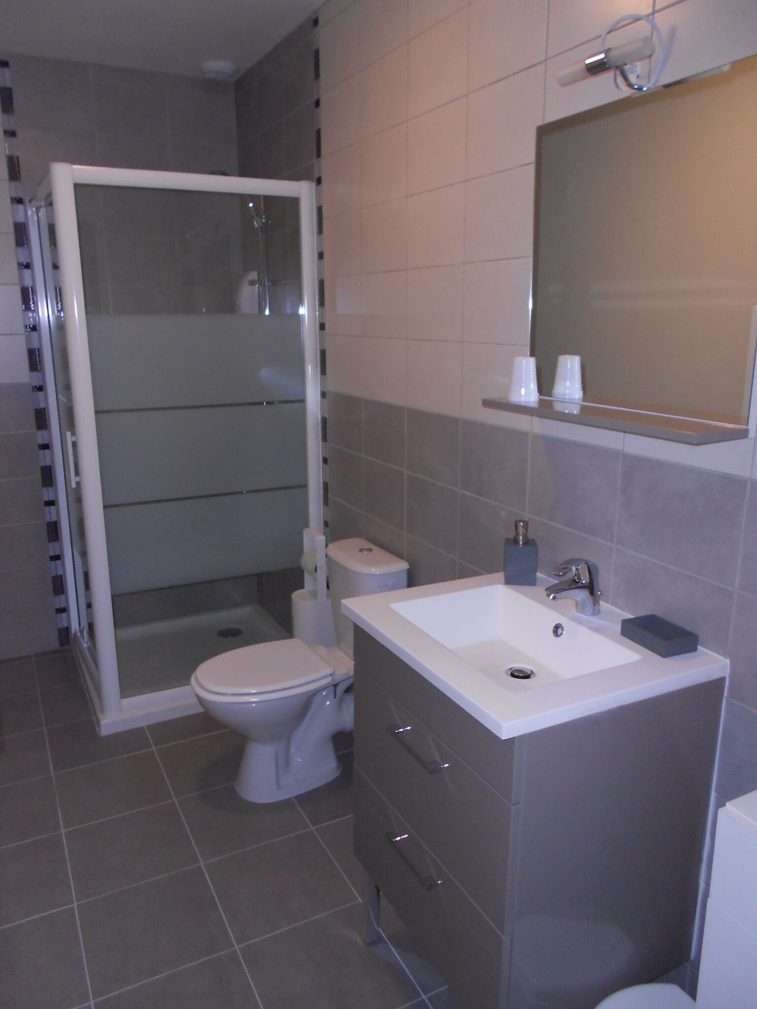 Ein modernes Badezimmer mit Dusche, Toilette, Waschbecken und Spiegel.