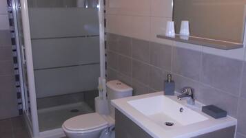 Ein modernes Badezimmer mit Dusche, Toilette, Waschbecken und Spiegel.