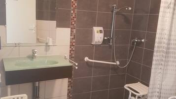 Uma casa de banho com chuveiro, pia, sanita e barra de apoio.