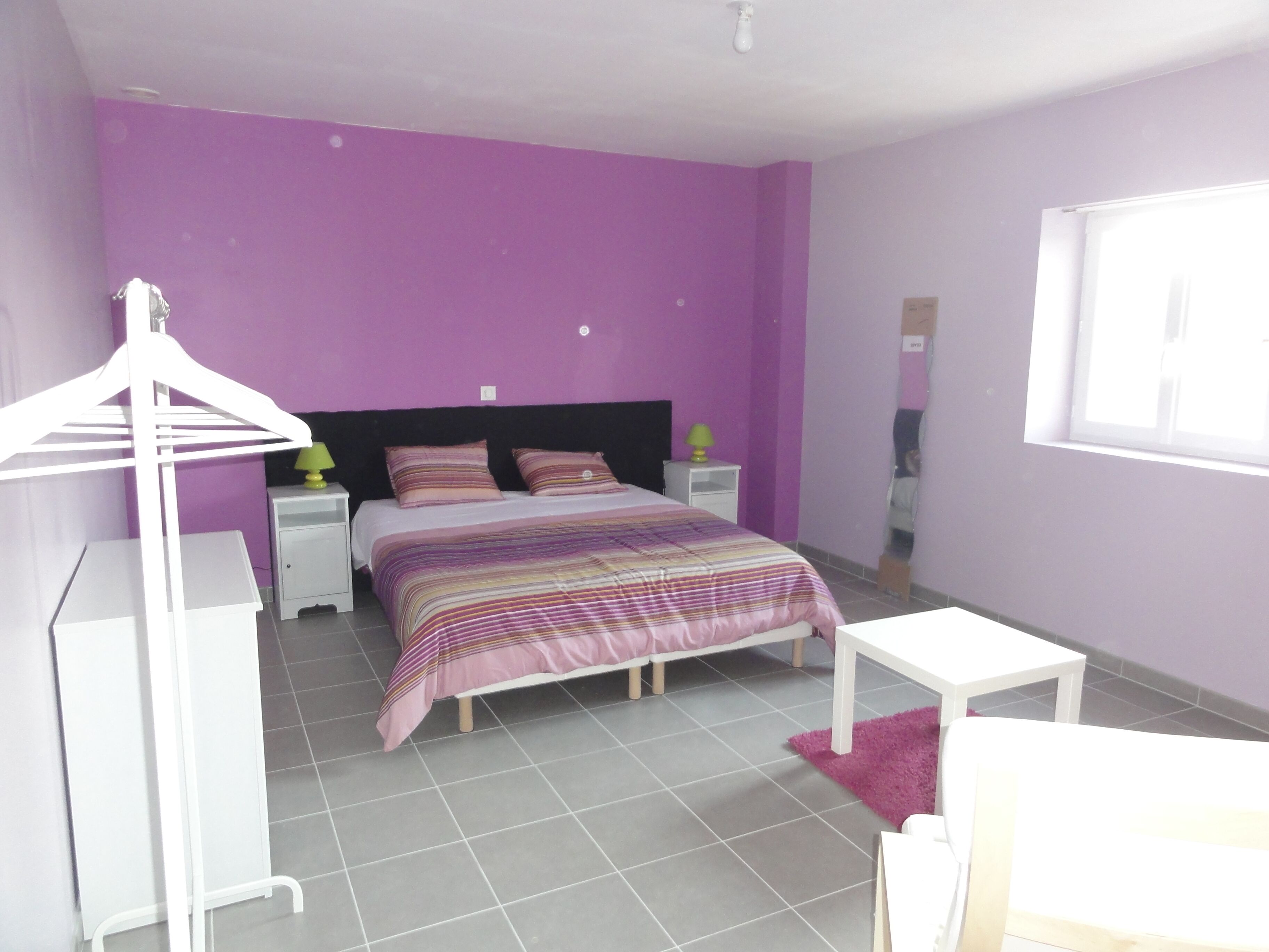 A bedroom with a bed, nightstands, a dresser, and a window.