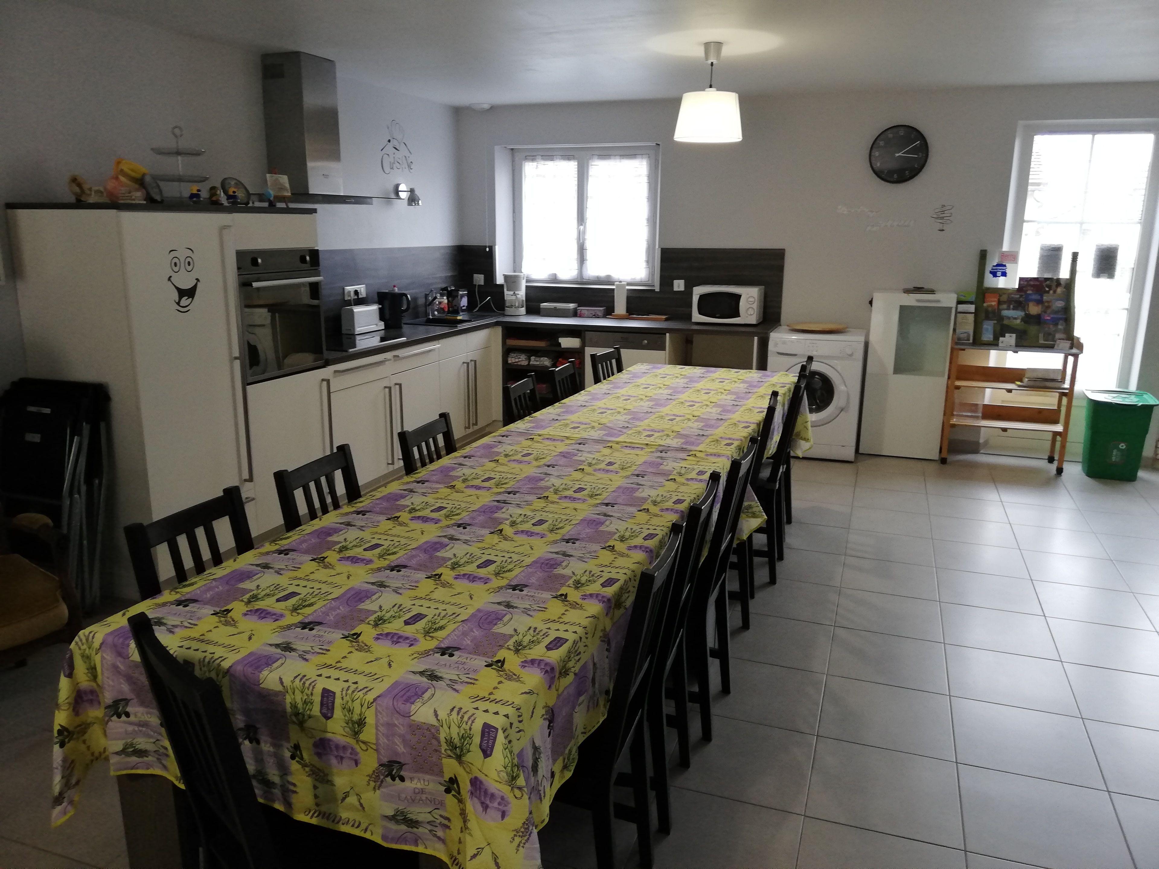 A compact kitchen with a dining area, a washing machine, and a small refrigerator.